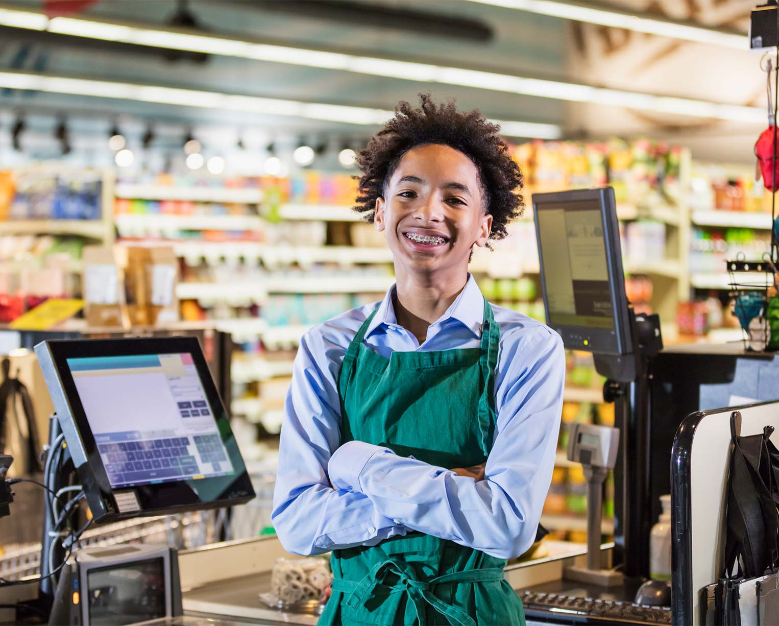 Young male adult working at retail store in front of a cash register.