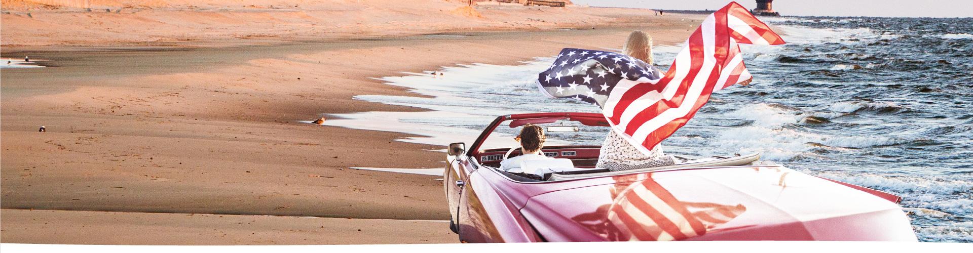 Car on beach with American flag